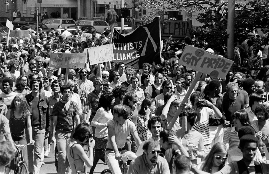 people marching with signs, one reads "Gay Pride"