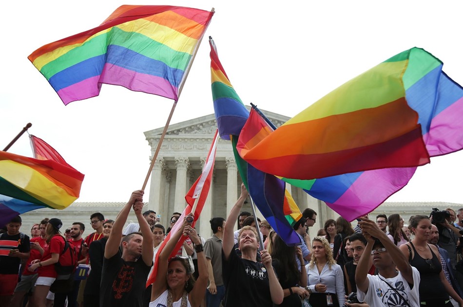 people waving Pride rainbow flags in front of the U.S. Supreme Court