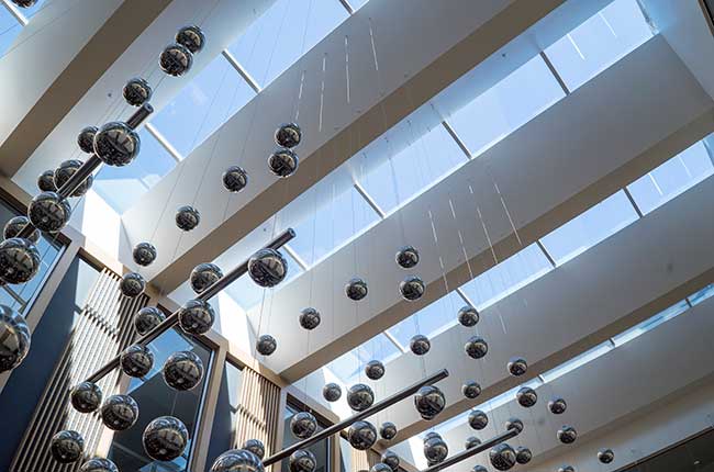 floating steel balls hanging from a skylighted ceiling