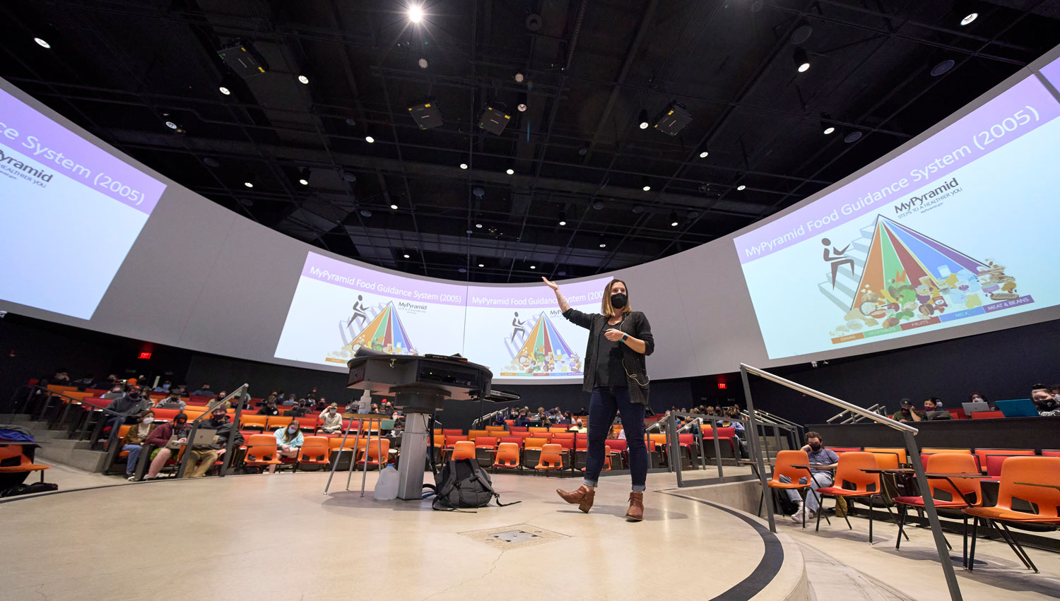 professor teaching in auditorium surrounded by students