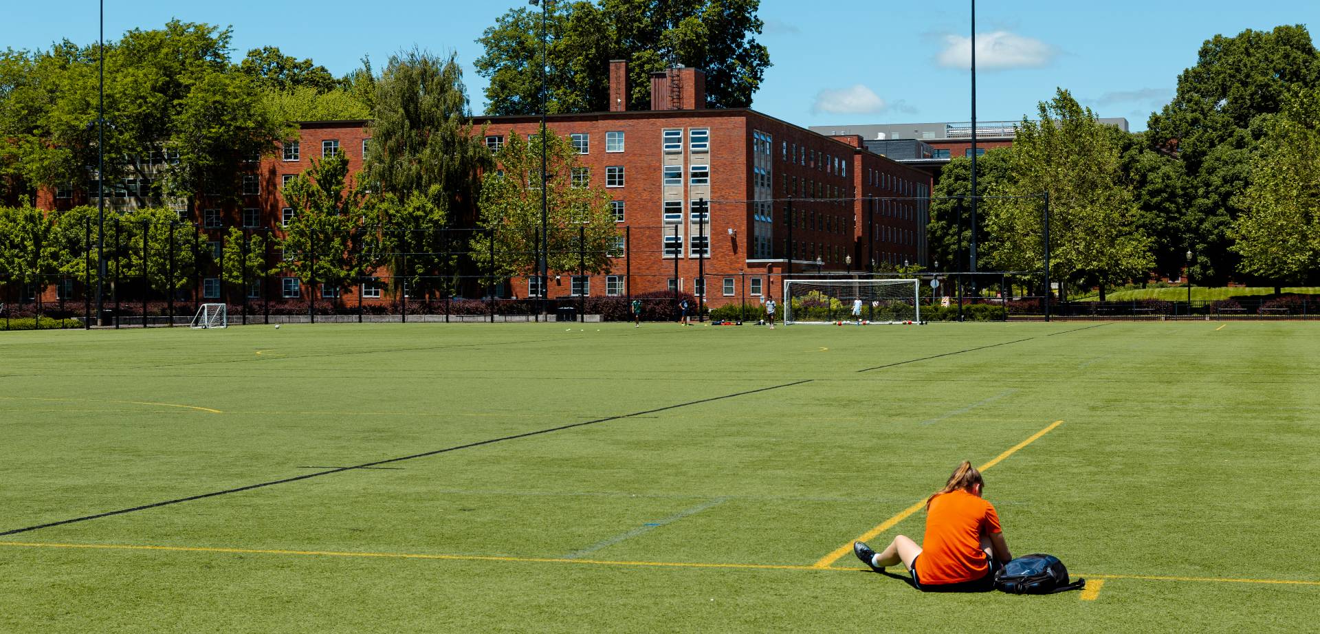 person sitting in a large field surrounded by brick buildings
