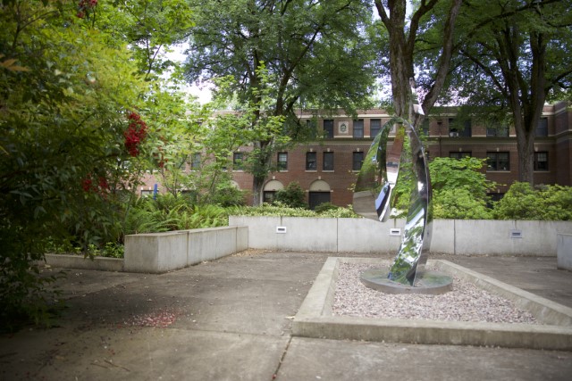 reflective chrome sculpture surrounded by shrubs