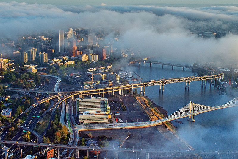 aerial of downtown Portland with clouds floating over buildings and bridges