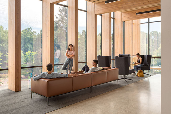 row of armchairs next to floor to ceiling windows alternating with wood paneling