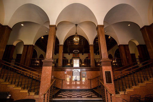 wooden staircase with overhead arches that splits left and right up the lobby of the Women's Building