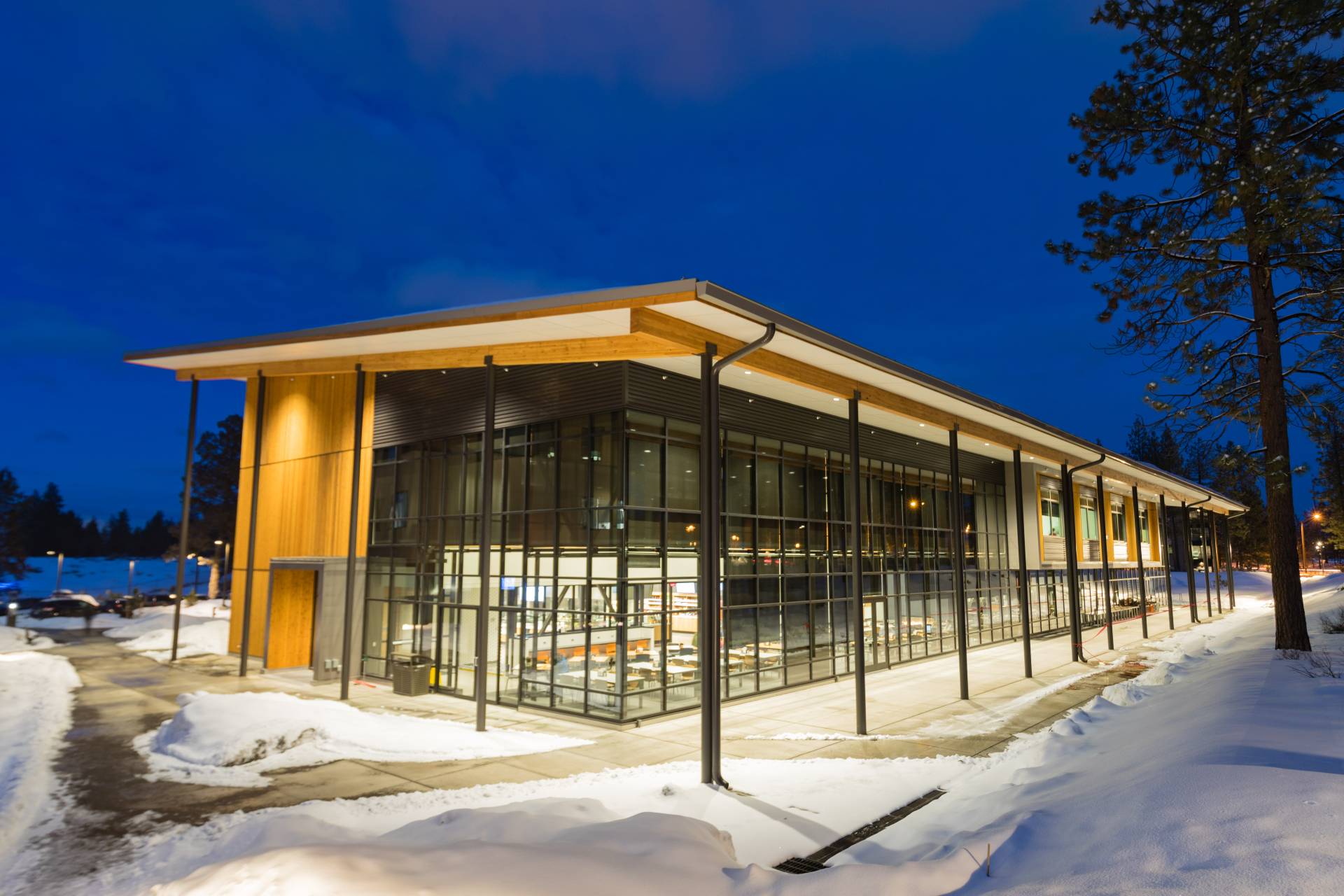 building with mostly glass walls sits in a snowy scene