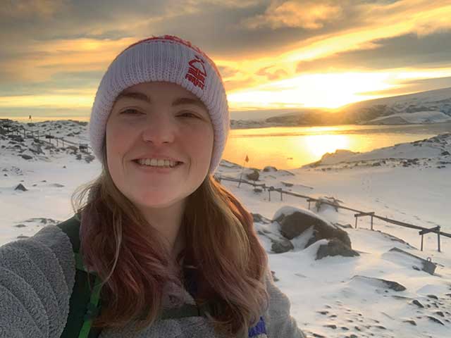 Guila Woods standing in front of a sunrise with a snowy landscape