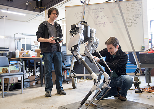 two people working with a bi-pedal robot