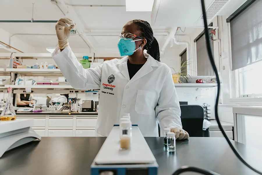 scientist in lab coat holding up a vial