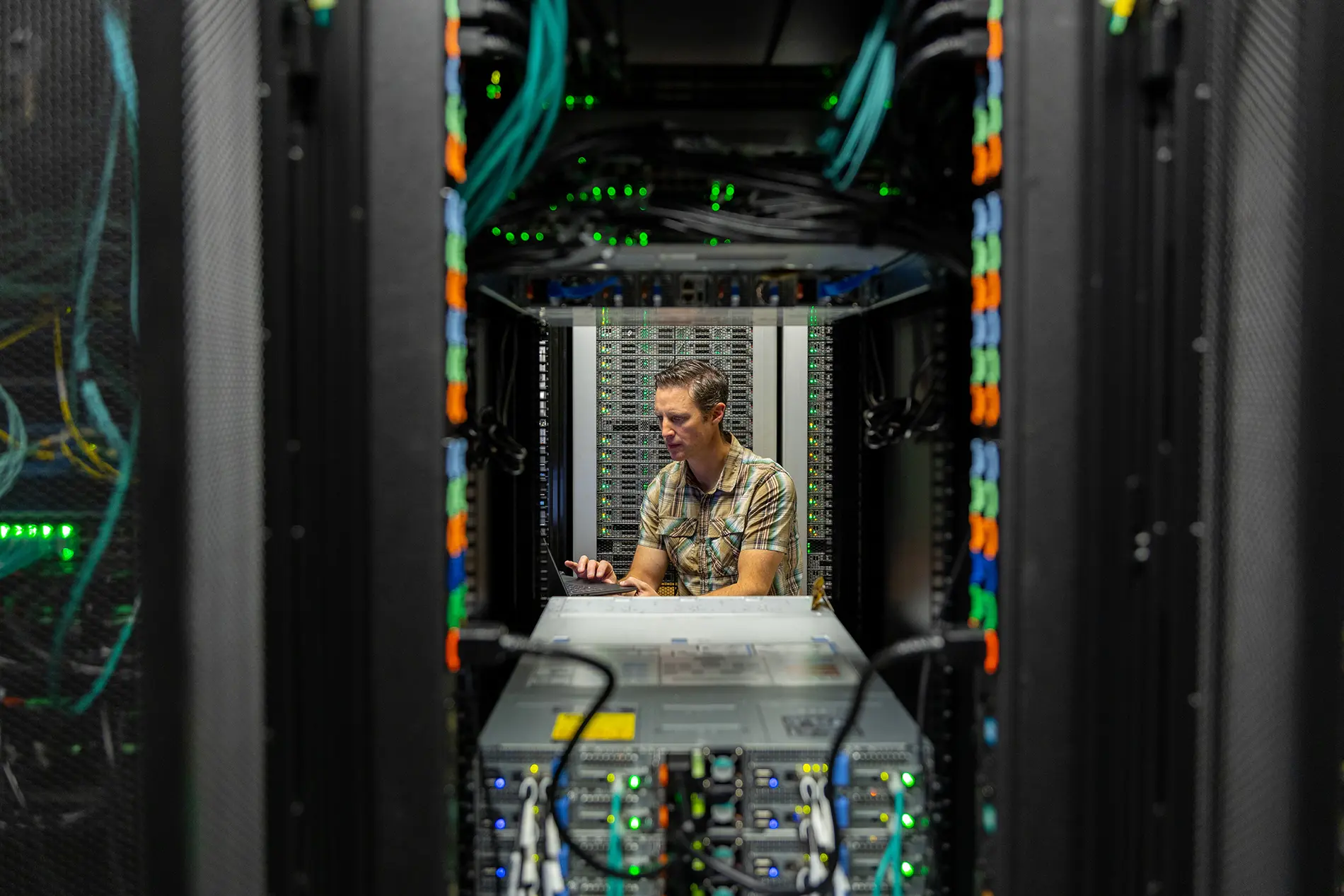 person in a server room working at a laptop