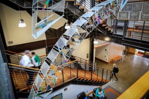people walking on stairway underneath glass art sculpture