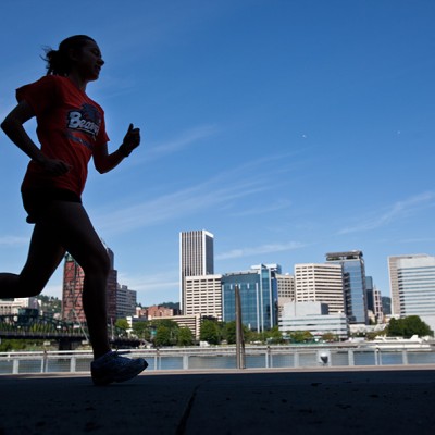 person running with the downtown Portland in the background