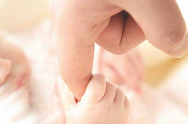 baby holding onto adult finger